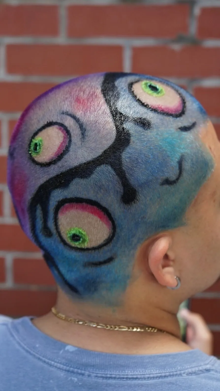 Painted hair design with bright cartoon eyes on a buzzed head